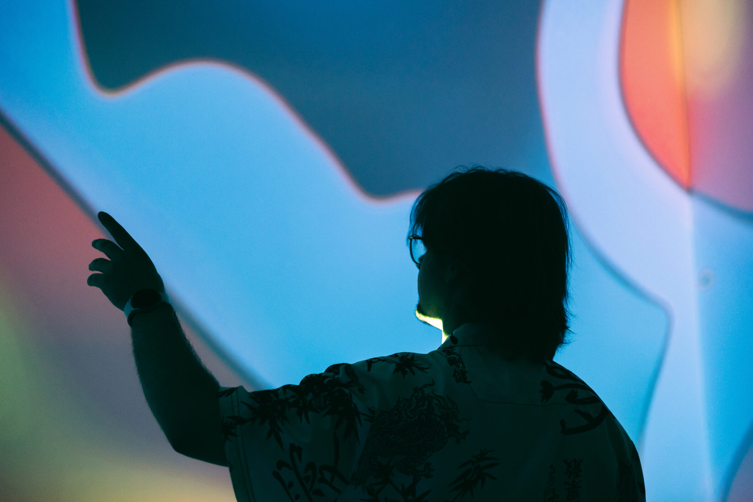 Besucherin steht im immersiven Raum des mpk umgeben von welligen, farbenfrohen Formen