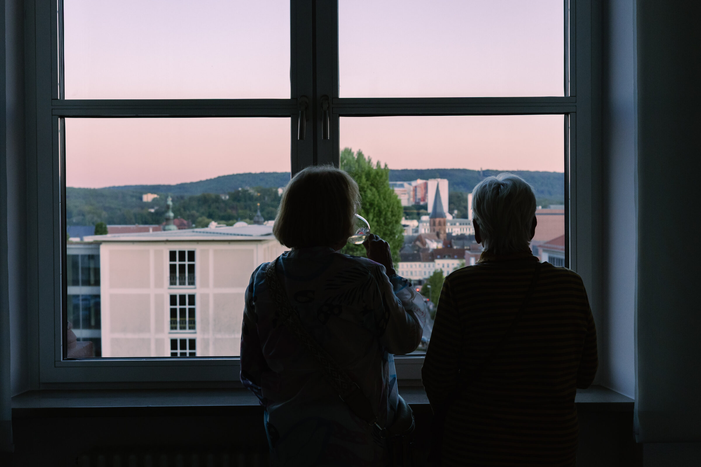 2 Besucherinnen des mpk trinken Wein und schauen sich den Sonnenuntergang über Kaiserslautern an