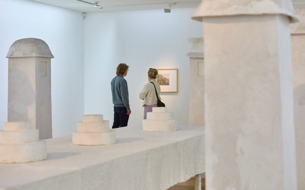 Besucher:innen stehen in der neuen Sammlung des mpk zwischen Kunstskulpturen