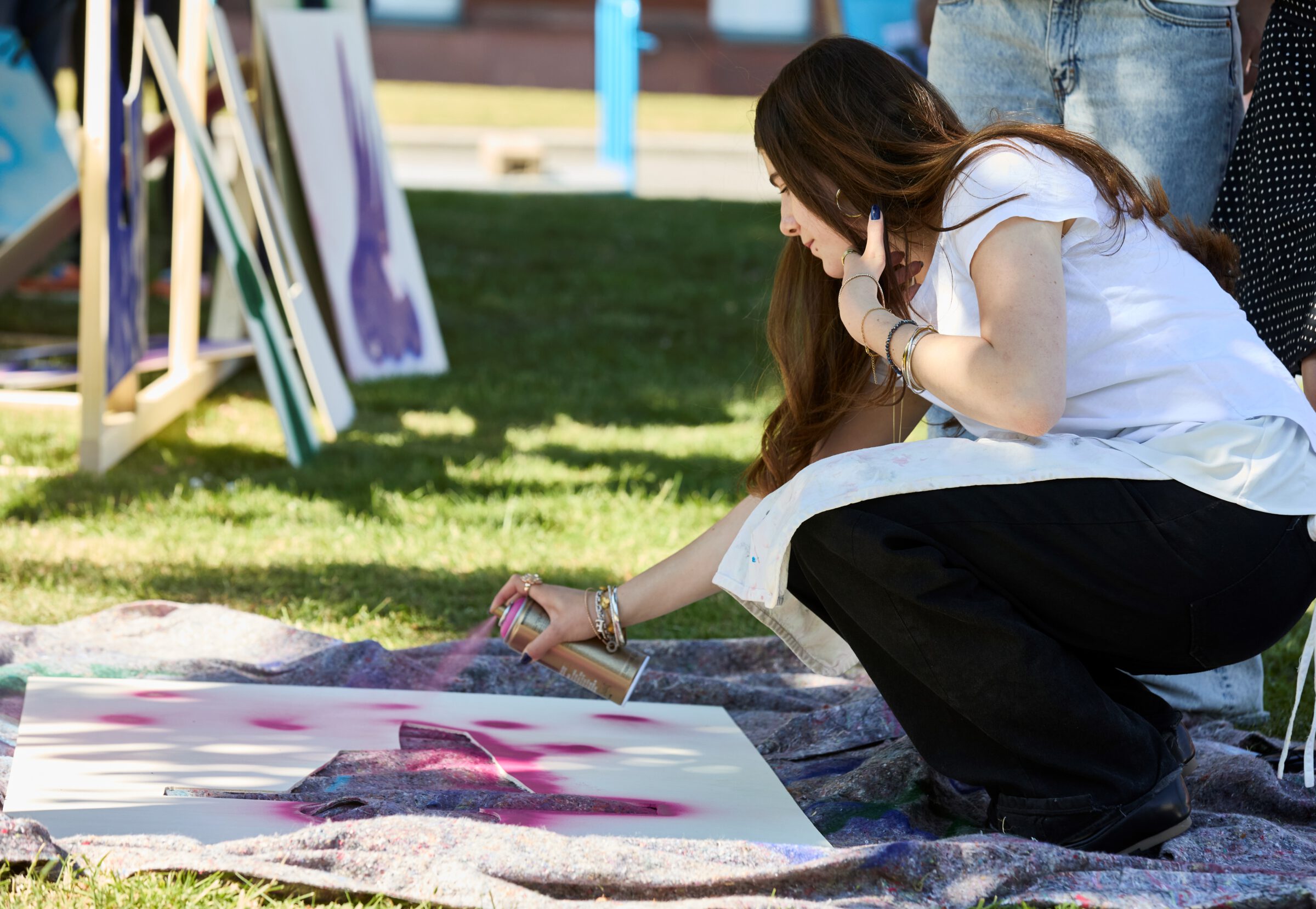 Kunstvermittlerin Flora sprüht mit einer Faqrbdose auf eine Holplatte auf dem Museumsvorplatz des mpk.