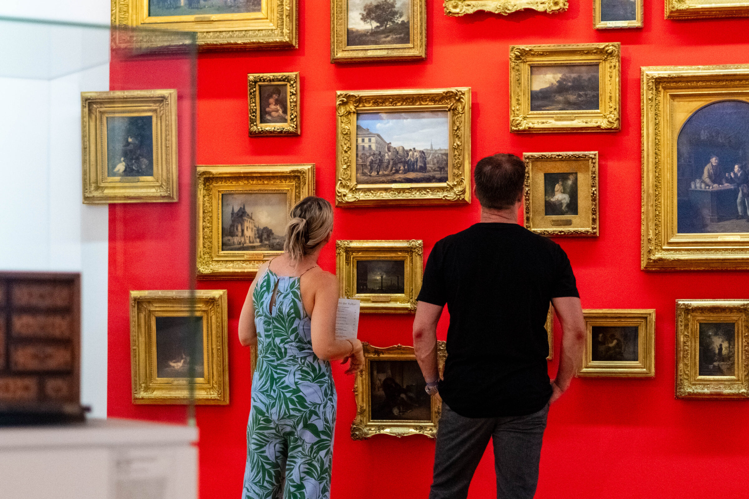 Raumansicht der Sammlungsneupräsentation mit verschiedenen Kunstwerken vor einer knallroten Wand.